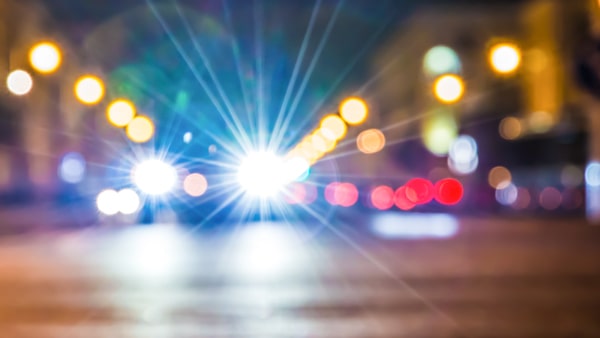 When a car with bright headlights comes toward you at night, you should: