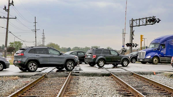 Before you reach the intersection, when crossing railroad tracks in slow traffic, you should: