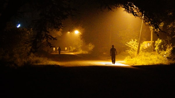 When driving in traffic at night on a dimly lit street, you should: