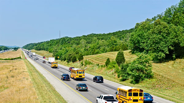 If a school bus stops to unload children on a four-lane highway, divided by a four-foot paved strip, vehicles traveling in the opposite direction are: