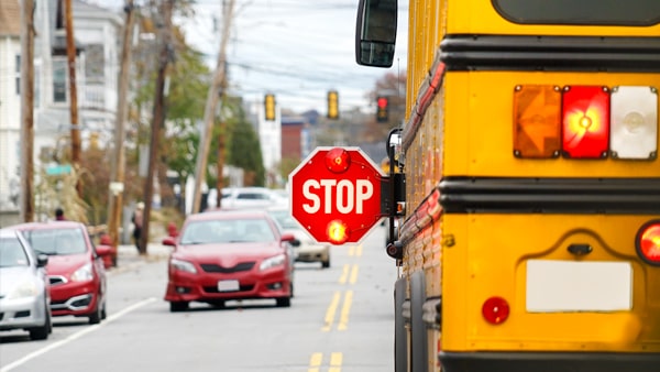 What does it mean when a school bus is stopped and its red lights are flashing?